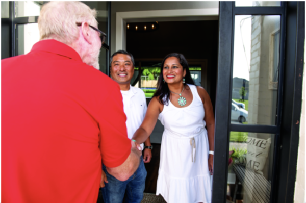 hvac technician shaking hands with homeowners in the doorway of their home