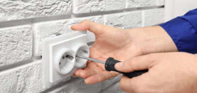 Electrician repairing socket on brick wall